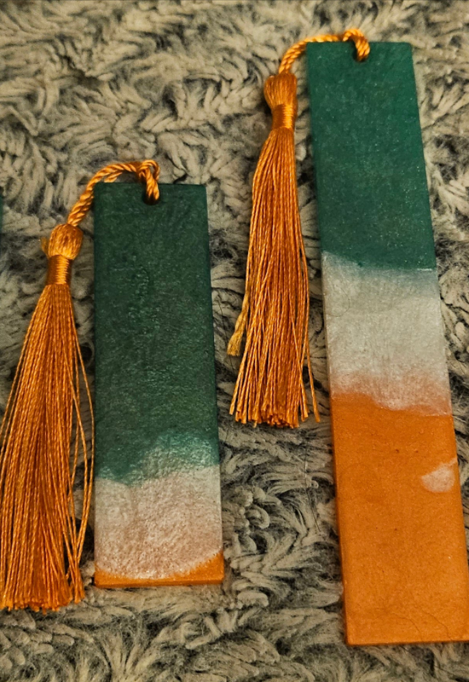 Two decorative bookmarks with tassels on a textured surface